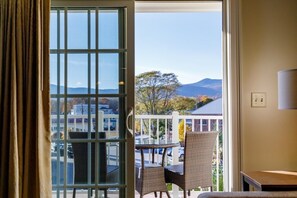 A room with a view of mountains, a balcony with wicker chairs, and a table. - Lincoln NH | Ski Retreat | Pool, Near Loon & Hiking Trails (Lincoln)