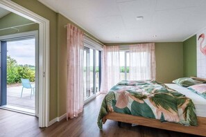 A bedroom with a bed, curtains, and a view through the glass door. - Holiday home with 1 bedroom (Zonnemaire)