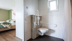 Een kleine badkamer met toilet, douche en raam.