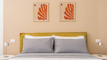 A bed with a white textured blanket, two gray pillows, and a yellow headboard.