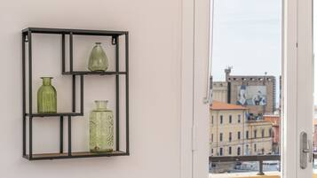 A room with a black metal shelf holding three glass vases.