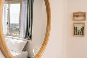 Ein Schlafzimmer mit einem Bett, einem Fenster und zwei gerahmten Bildern an der Wand.