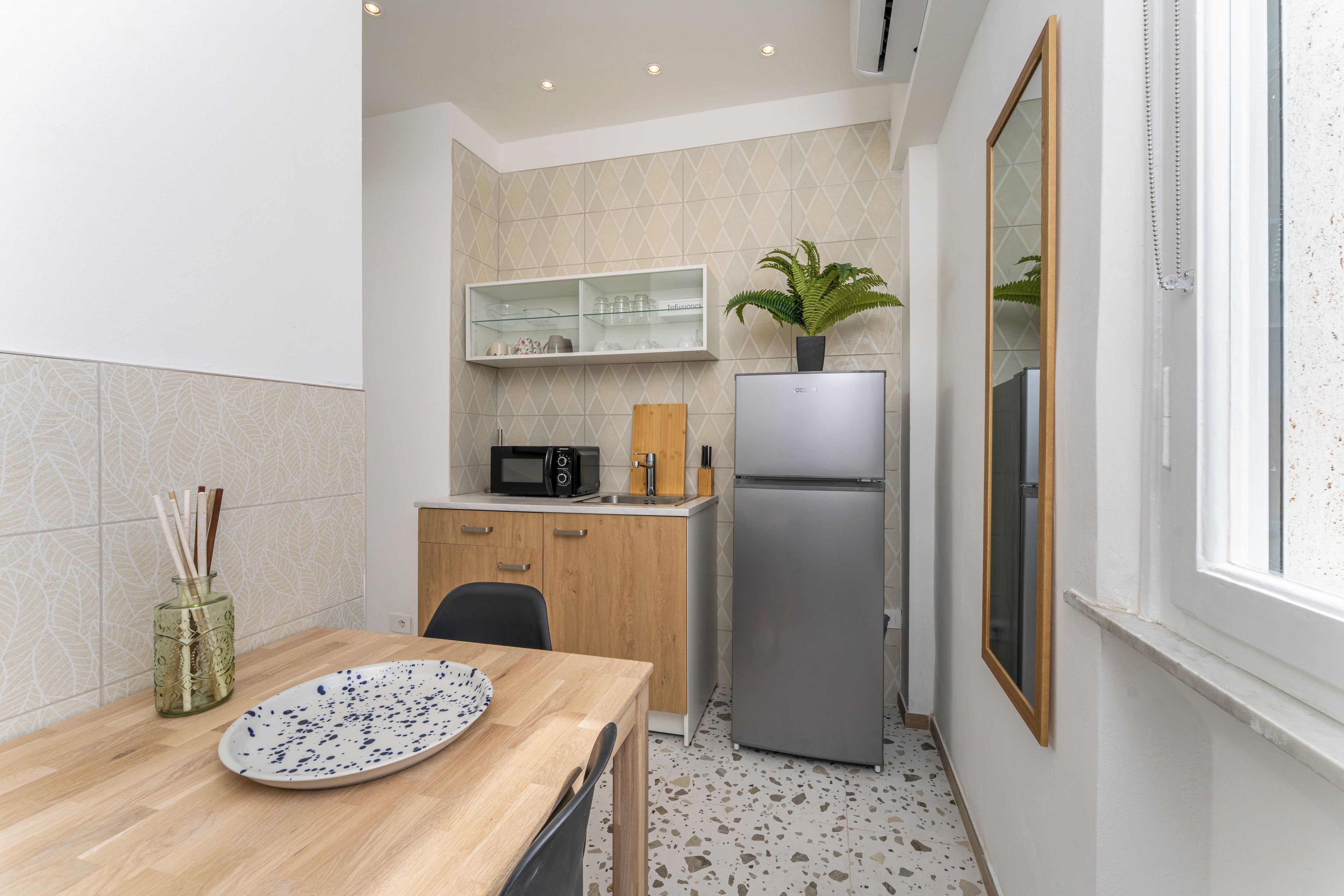Une cuisine compacte équipée d’un four à micro-ondes, d’un réfrigérateur et d’une petite table à manger avec une assiette.