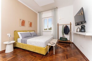 Un dormitorio moderno con cama, mesita de noche, lámpara y vistas al exterior.