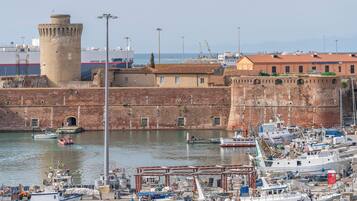 A harbor with boats docked, a historic fort, and a building with a red roof.