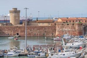Ein Hafen mit vertäuten Booten, eine historische Festung und ein Gebäude mit rotem Dach.