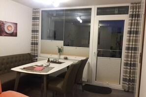 A dining area with a table, chairs, a bench, and a window with curtains. - Holiday apartment with 2 bedrooms (Altenau)