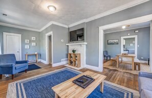 Ein Wohnzimmer mit Kamin, einem darüber montierten Fernseher und einem Essbereich mit Tisch und Stühlen.