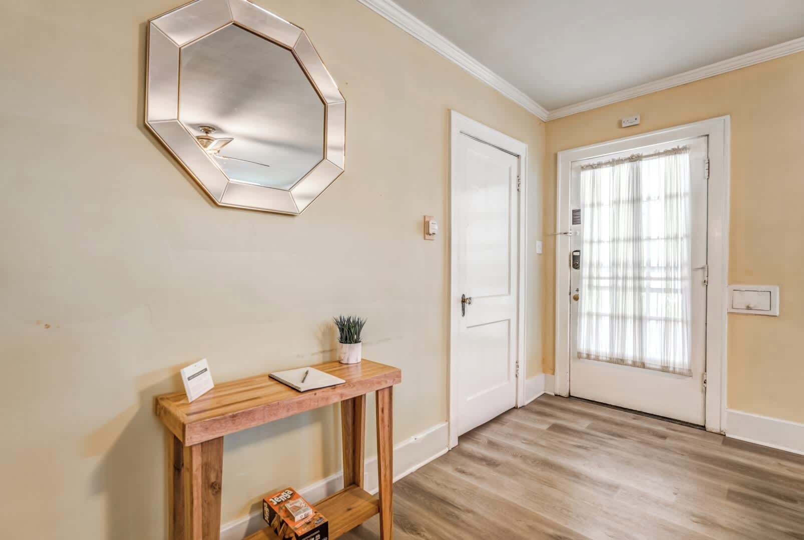 A hallway with a wooden console table, a mirror, and a door with a window.