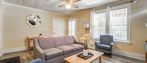 A living room with a sofa, armchair, coffee table, and a ceiling fan.