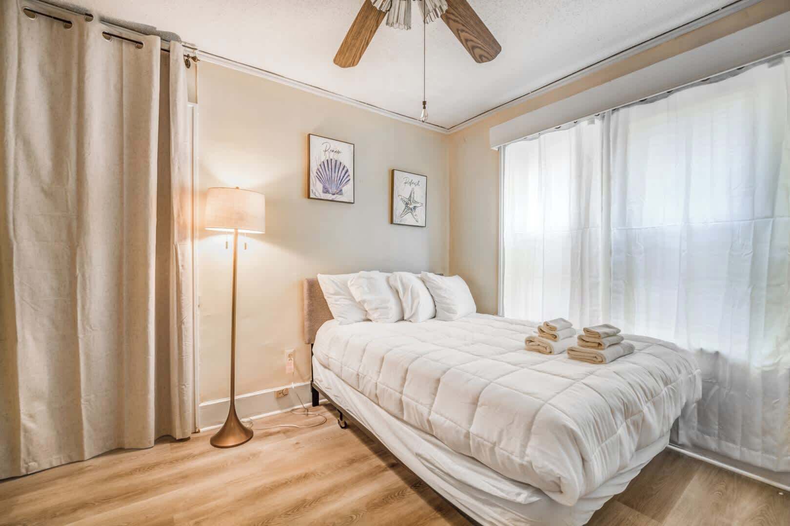A bedroom with a bed, a floor lamp, and two wall art pieces.