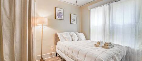 A bedroom with a bed, a floor lamp, and two wall art pieces.