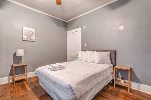 Ein Schlafzimmer mit einem Bett, Nachttischen, einer Lampe und einem Gemälde an der Wand.