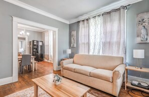 Ein Wohnzimmer mit einem beigen Sofa, einem Holztisch und einem Essbereich mit Tisch und Stühlen.