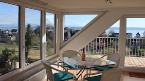 Een balkon met een glazen tafel, stoelen en een fles.