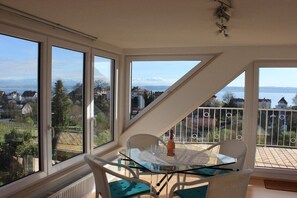 Een balkon met een glazen tafel, stoelen en een fles.