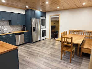 Cocina moderna con electrodomésticos de acero inoxidable, comedor con muebles de madera y suelo con un patrón de espiga.