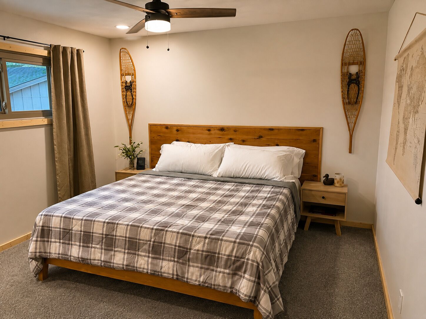 A bedroom with a wooden bed, a nightstand, a ceiling fan, and a window with curtains.