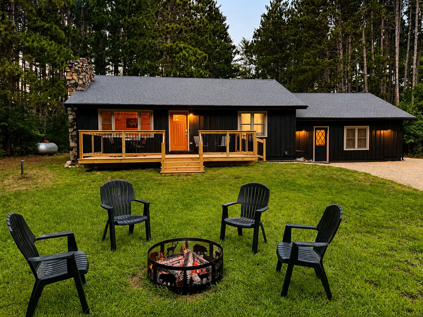 Une cabane avec une terrasse, un foyer et quatre chaises.