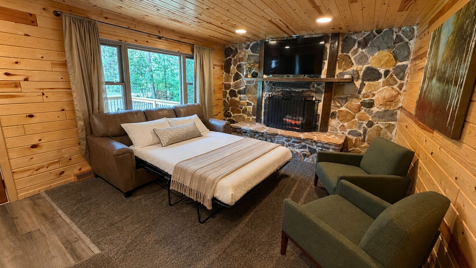 A cozy room with a bed, a stone fireplace, a television, and a window with curtains.