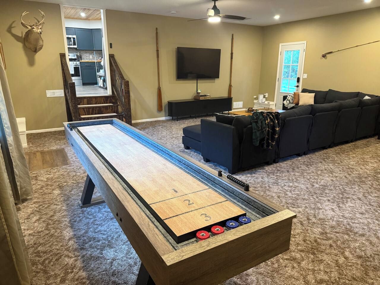 A shuffleboard table in a living room with a sofa and a television.
