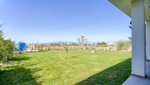 A grassy outdoor area with a clear view of distant hills and a blue water tank. - Calabria – Vacation Home with a Garden, Ocean View, and Close to the Beach Near Tropea and Pizzo (Località Punta Safò Briatico)