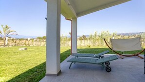 A covered outdoor area with a green lawn, two lounge chairs, and a hammock. - Calabria – Vacation Home with a Garden, Ocean View, and Close to the Beach Near Tropea and Pizzo (Località Punta Safò Briatico)
