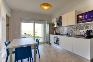 A modern kitchen with a dining area, a television mounted above the counter, and a patterned backsplash. - Calabria – Vacation Home with a Garden, Ocean View, and Close to the Beach Near Tropea and Pizzo (Località Punta Safò Briatico)