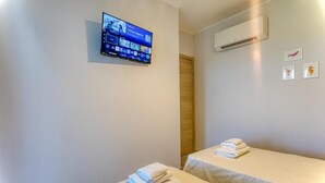 A hotel room with two beds, a TV mounted on the wall, an air conditioning unit, and a door. - Calabria – Vacation Home with a Garden, Ocean View, and Close to the Beach Near Tropea and Pizzo (Località Punta Safò Briatico)