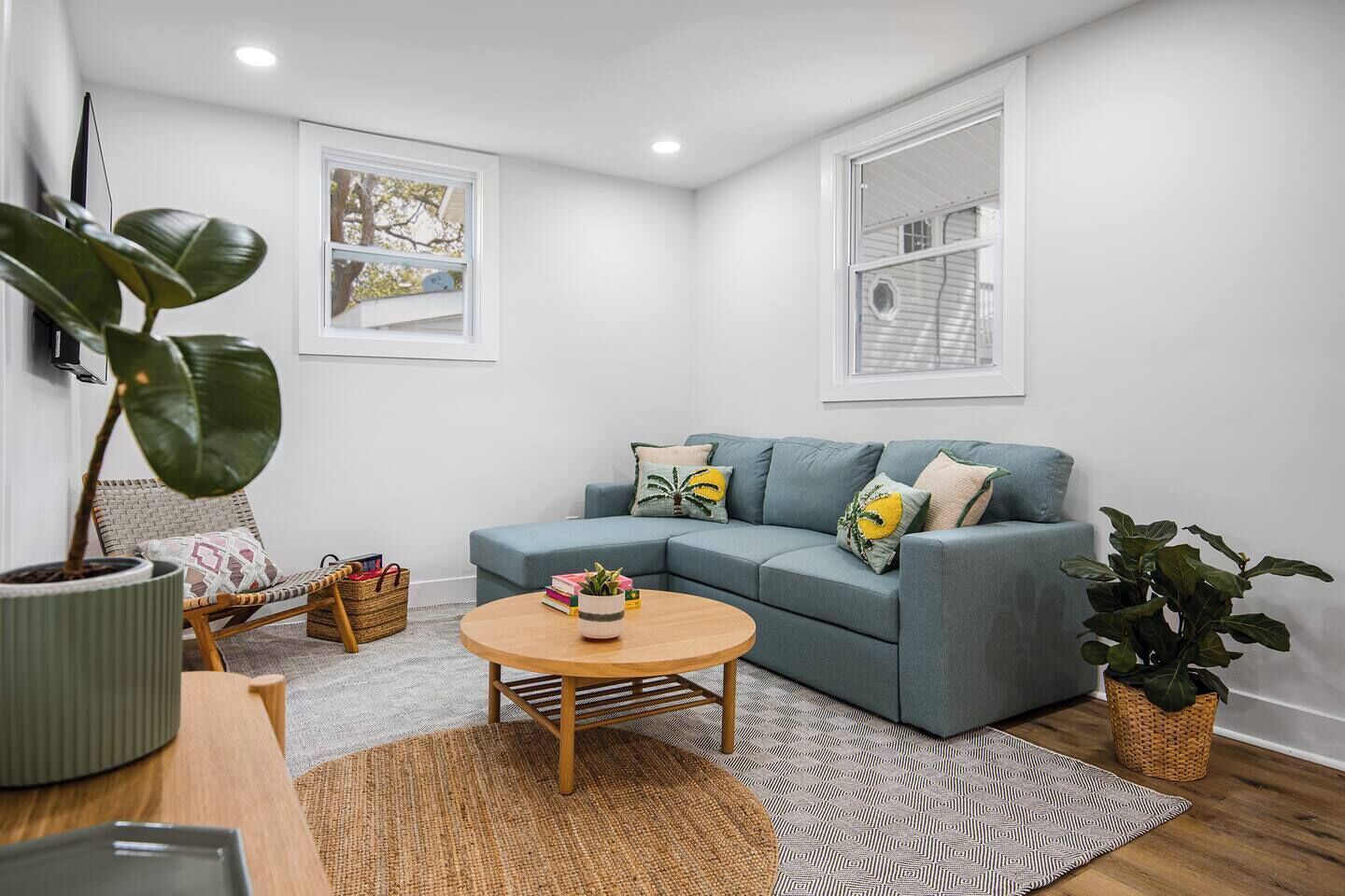 A living room with a grey sofa, a round wooden coffee table, and a large potted plant.