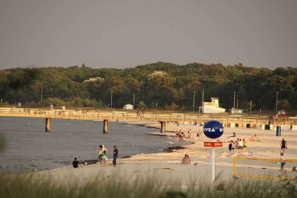 A beach with a volleyball net, people playing, and a sign that says 'AVEA NT'.