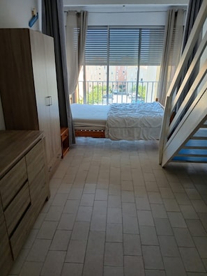 Un dormitorio con cama, armario y ventana con persianas.