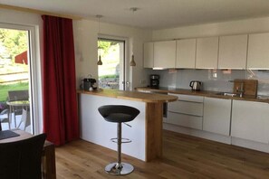 A modern kitchen with a wooden island, white cabinets, and a red curtain. - Holiday apartment with 2 bedrooms (Füssen)