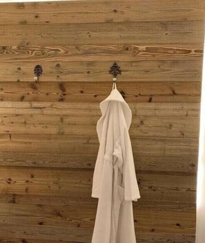 Ein weißes Kleidungsstück hängt an einer Holzwand mit schlichtem, rustikalem Design.