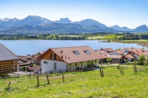 A lakeside village with houses, a wooden cabin, and mountains in the background. - Holiday apartment with 2 bedrooms (Füssen)