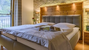 A bedroom with a large bed, a wooden headboard, a nightstand with a lamp, and a view of the outdoors. - Holiday home with 2 bedrooms (Waischenfeld)