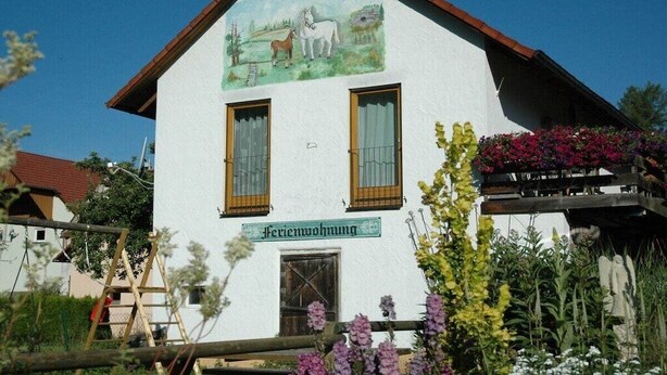 A building with a sign reading 'Ferienwohnung' and a mural of horses on the facade. - Holiday home with 2 bedrooms (Waischenfeld)