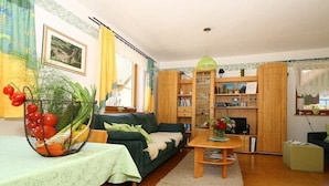 A cozy living room with a sofa, a dining table, a bookshelf, and a decorative plant. - Holiday home with 2 bedrooms (Waischenfeld)
