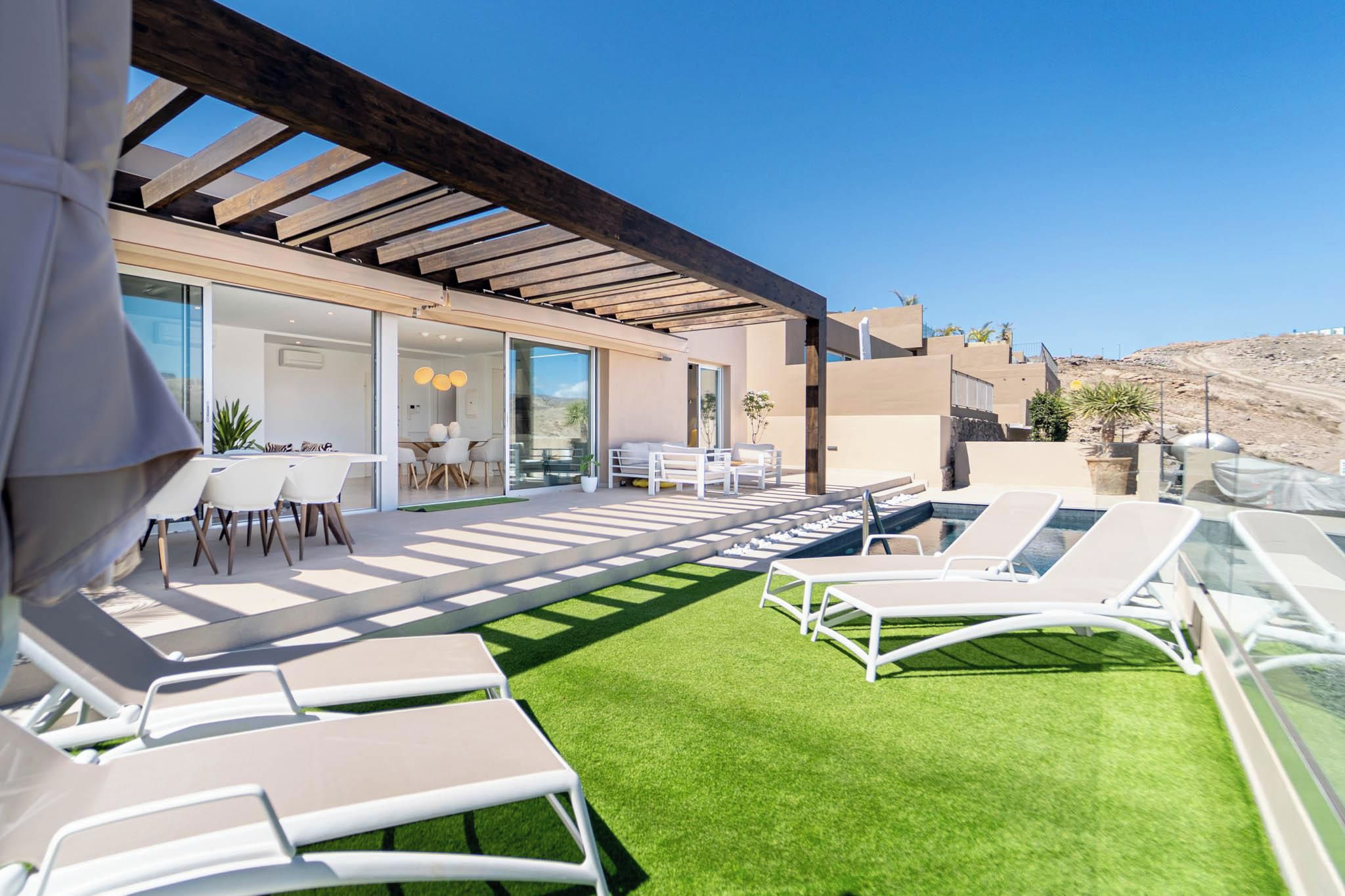 Eine moderne Terrassenanlage im Freien mit Pool, Liegestühlen und Essbereich.