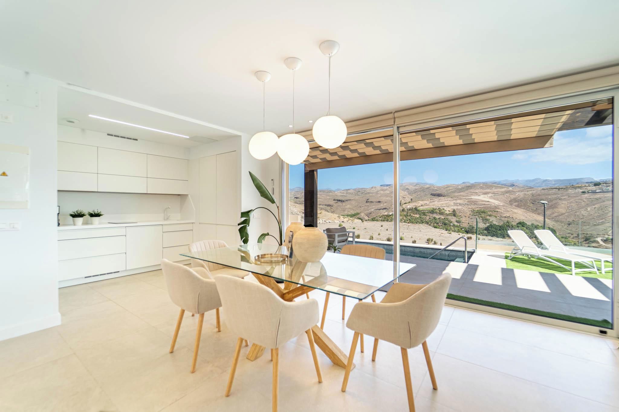 Una cocina moderna con gabinetes blancos y una mesa de comedor de vidrio con sillas.