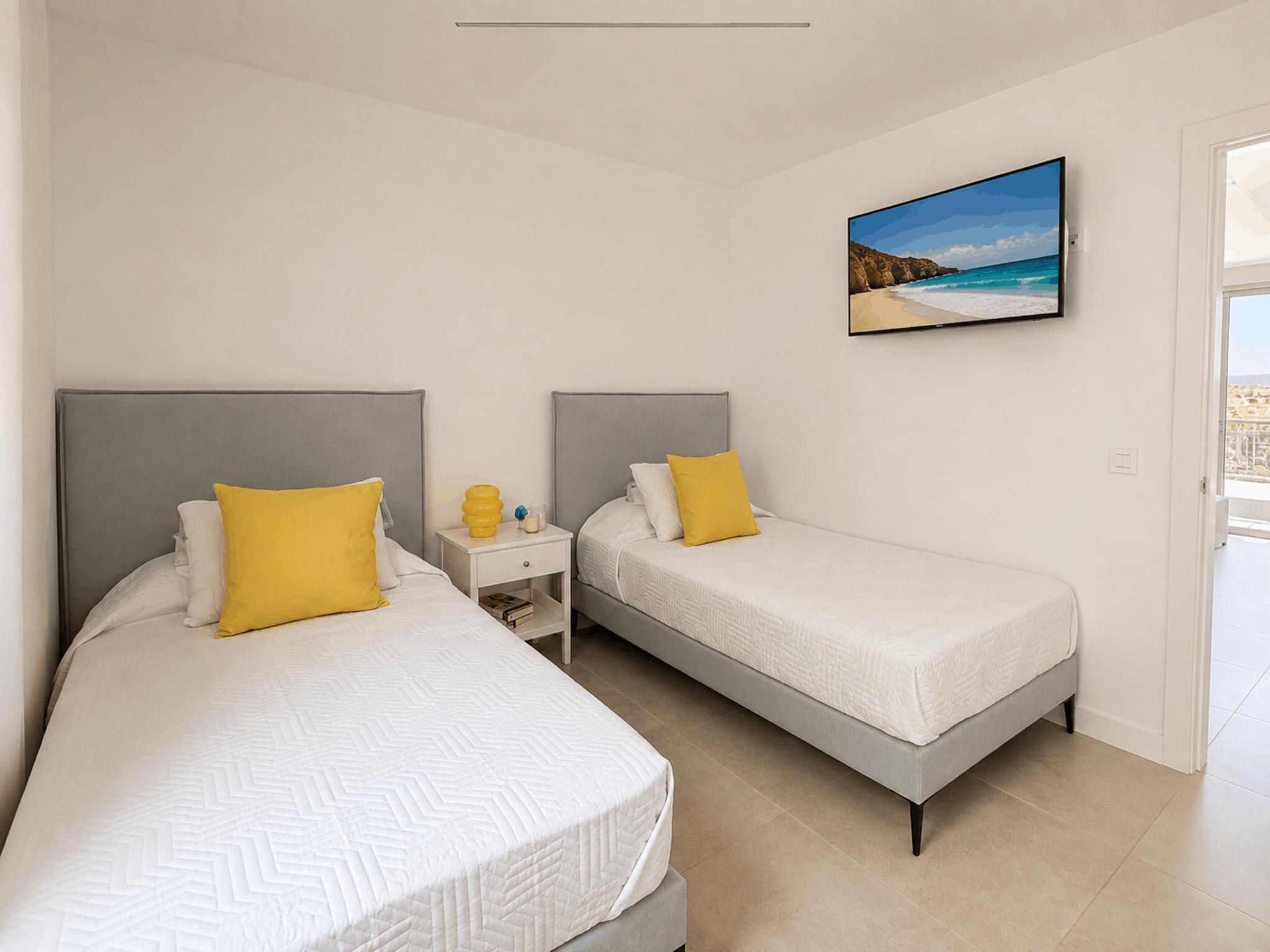 Une chambre d’hôtel avec deux lits, une table de chevet, un tableau et une vue sur la mer.