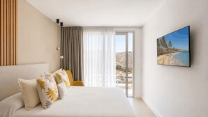 Habitación de hotel con una cama grande, vista a la playa y un cuadro en la pared.