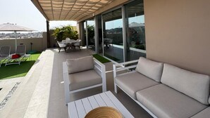 Un área de estar al aire libre con toldo, sofá, mesa y vistas de la ciudad.
