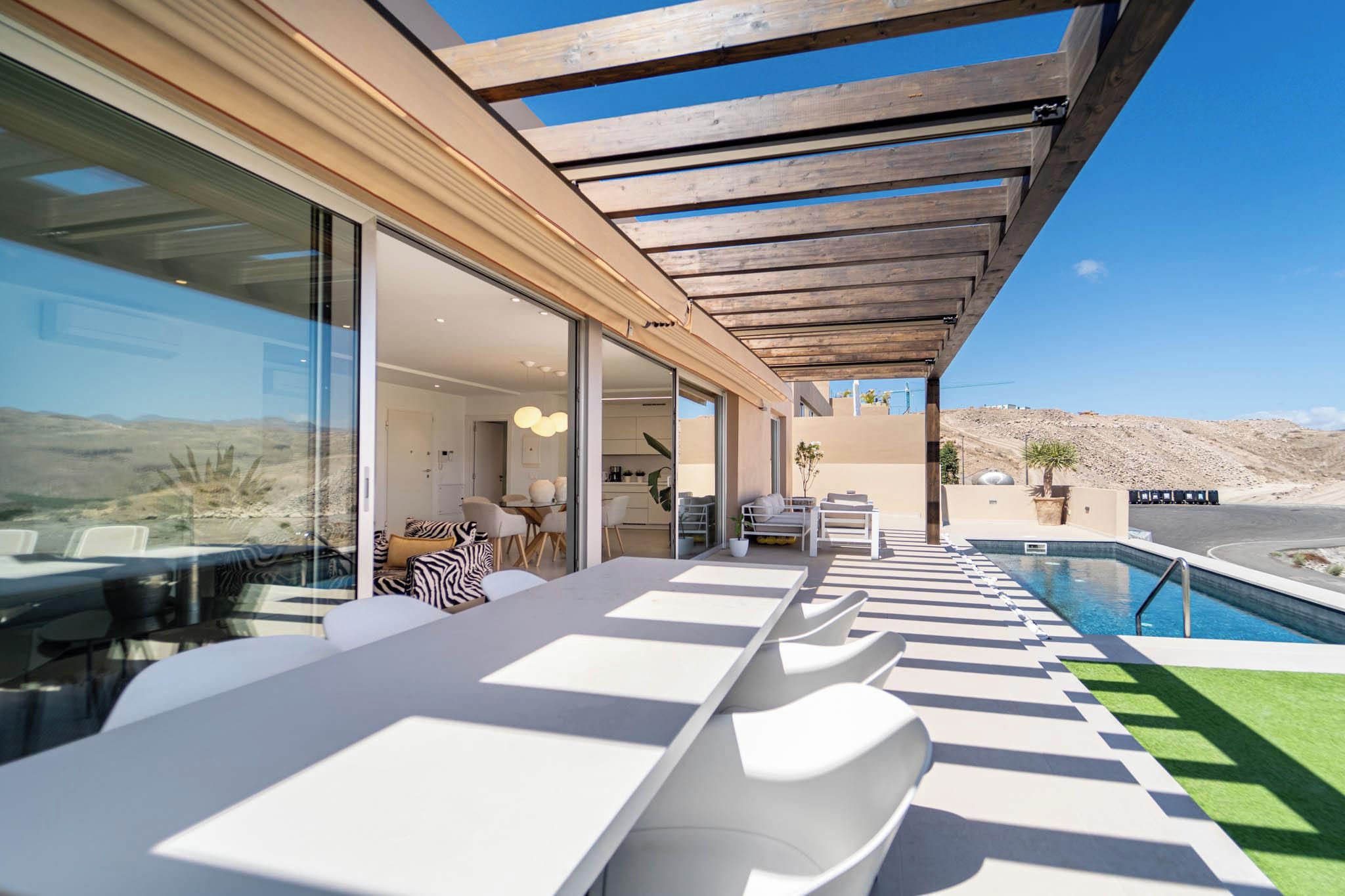 A modern outdoor seating area with a pool, large windows, and a view of the landscape.