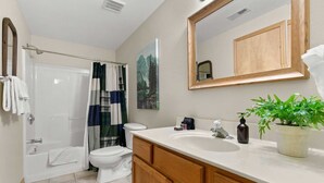 A bathroom with a shower, toilet, sink, and wooden cabinets.