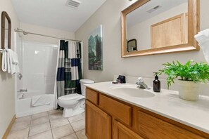 Ein Badezimmer mit Dusche, Toilette, Waschbecken und Holzschränken.