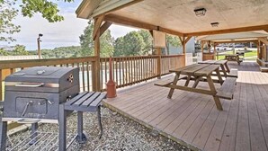 An outdoor patio with a barbecue grill, picnic tables, and a covered seating area.