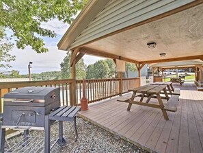 Eine Terrasse im Freien mit einem Grill, Picknicktischen und einer überdachten Sitzgruppe.