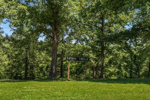 Un panneau indicateur portant l’inscription « SENTIERS NATURE », entouré d’arbres et d’herbe.