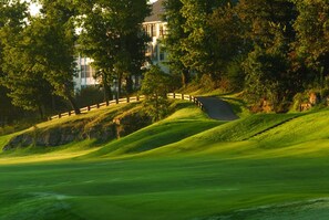 A golf course with a wooden fence, lush green grass, and a building in the background. - Big Cabin close to Silver Dollar City with 2 Living Areas, 150 acres, Private Lake/34 (Branson West)